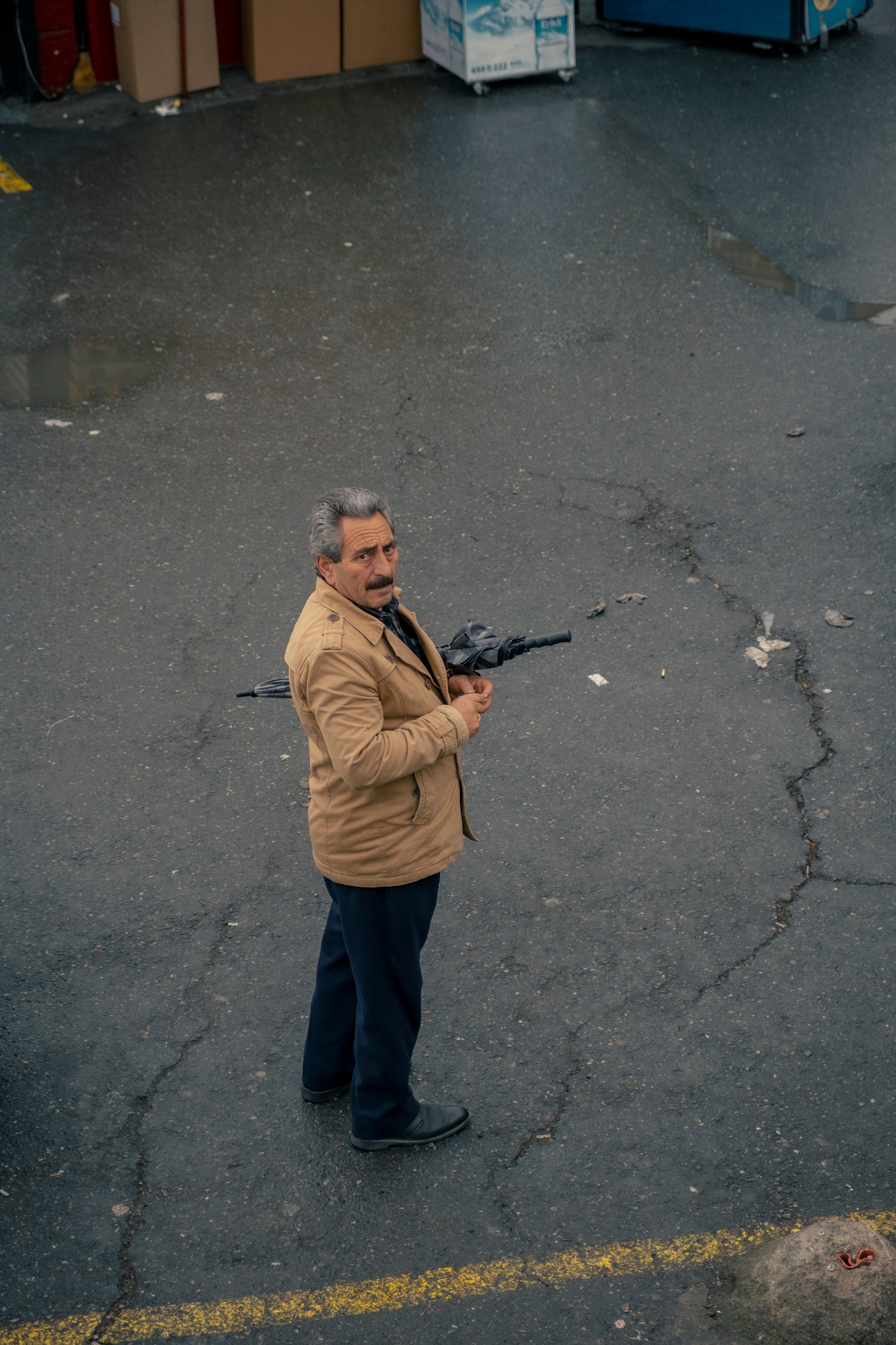 A man stands on a city street holding an umbrella. Outdoor urban setting.