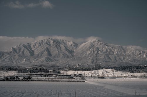 Free Snow-capped mountains rise above a serene town, capturing a winter wonderland scene with minimalist tones. Stock Photo