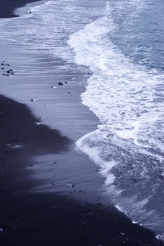 Stunning view of waves on a black sand beach in Puerto de la Cruz, Spain.