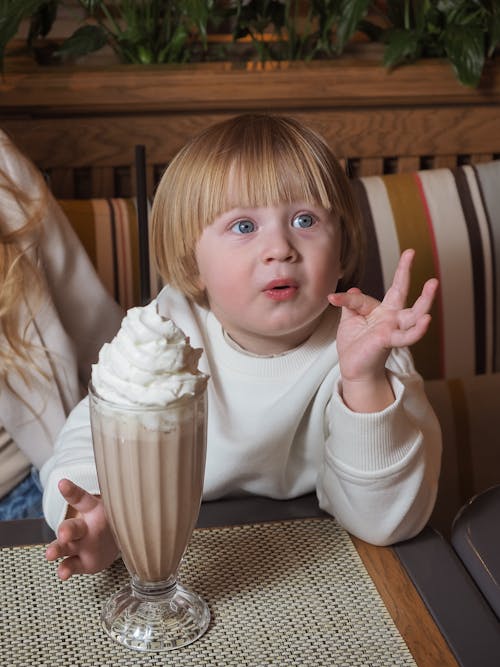 Photo of a Blond Baby Having Hot Chocolate with Whipped Cream