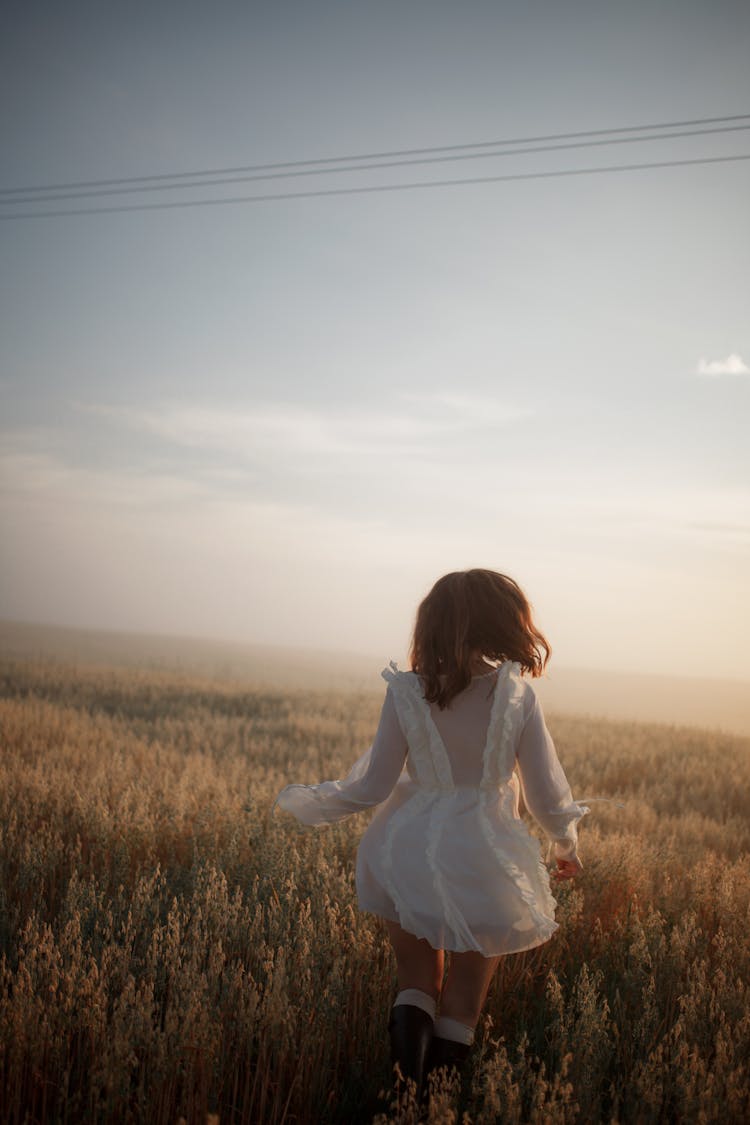 Woman In White Dress Running In A Field Of Dry Reeds