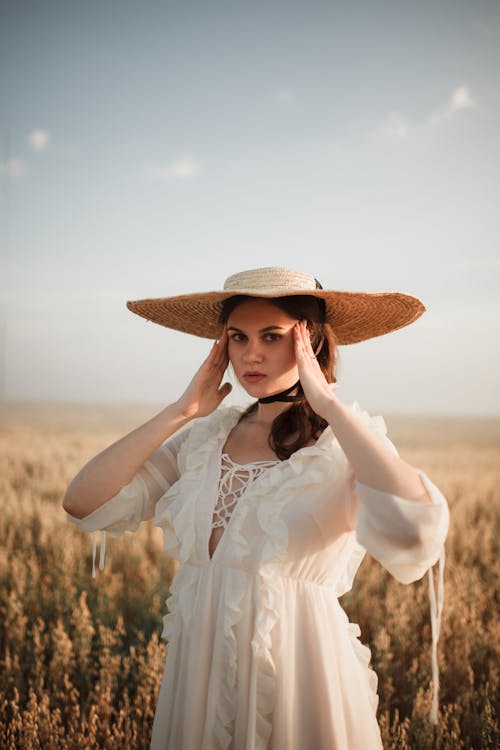 Woman in Hat and White Dress on Field