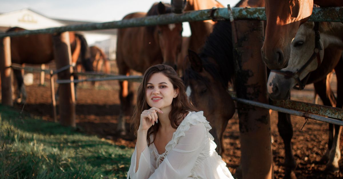 Woman In White Dress Squatting By Corral Fence Free Stock Photo woman-in-white-dress-squatting-by-corral-fence-free-stock-photo