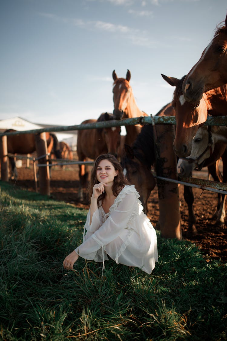 Woman In White Dress Squatting By Corral Fence