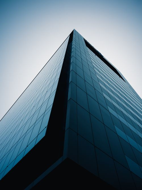 Free Dramatic low angle view of a sleek, modern skyscraper against a gradient blue sky. Stock Photo
