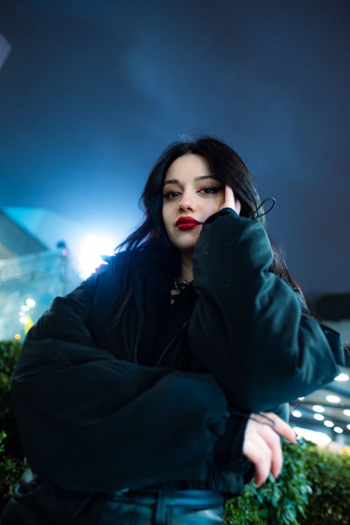 Free Stylish portrait of a woman in warm clothing under city lights at night. Stock Photo