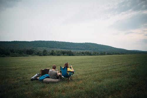 A Couple Sitting on Green Grass Field 