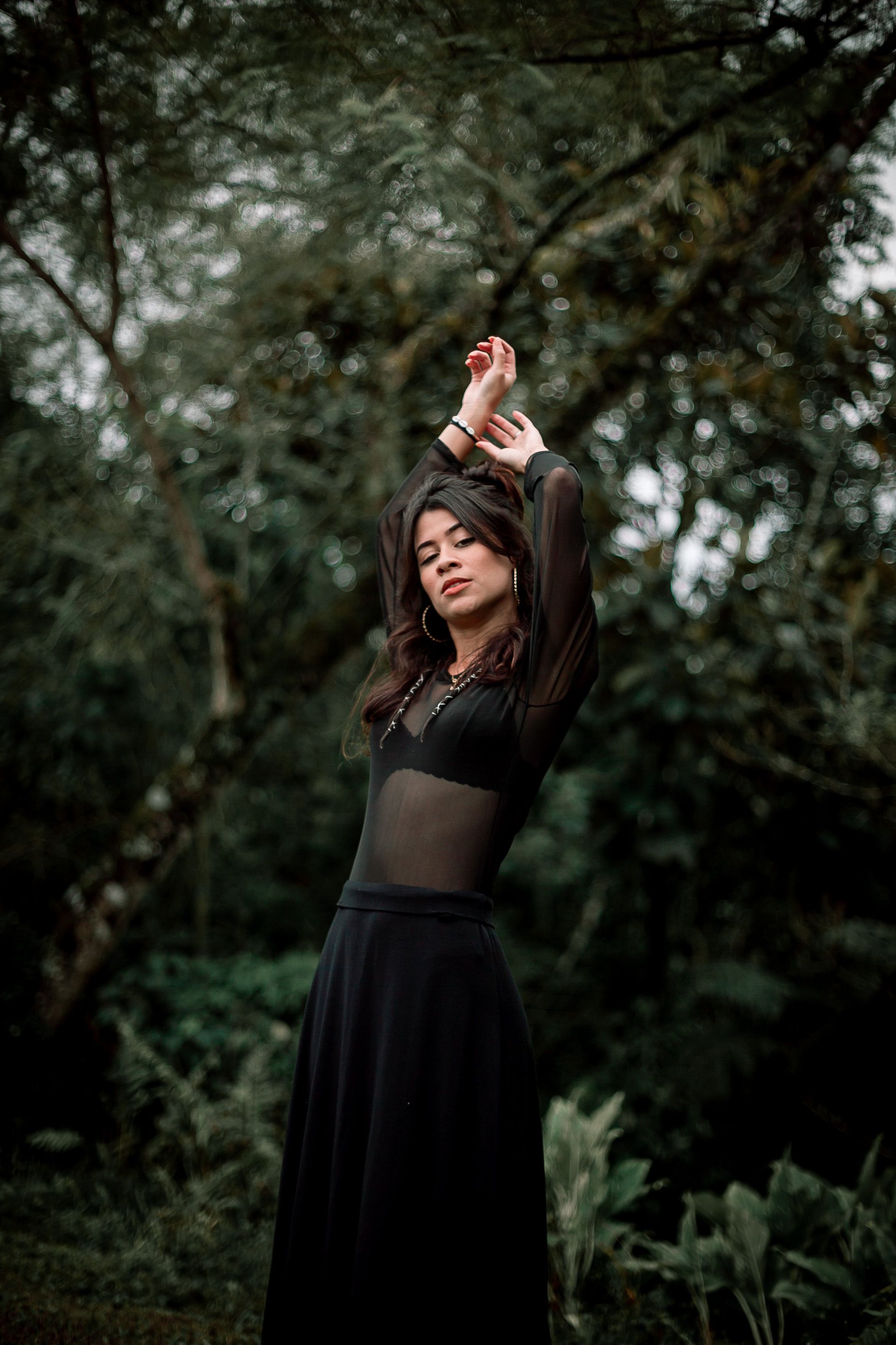 A Woman in Black Dress Posing while Raising her Hands · Free Stock Photo