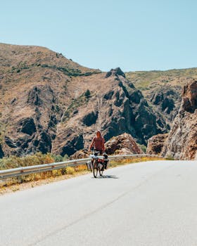 Man cycling on a scenic mountain road in Aluminé, Argentina, surrounded by rocky landscapes.
