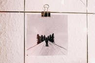 墙上夹着一幅用黑色墨水绘有雪和树木的冬季场景的画