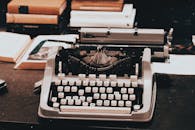 桌上摆着一台古董打字机的特写，周围堆满了书籍，充满了经典的复古气息