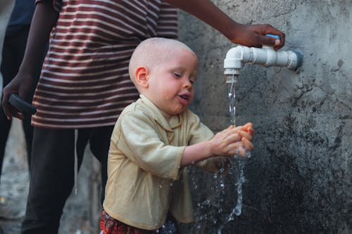 Boy Standing by Faucet on Wall and Washing Hands