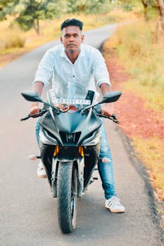A man rides a motorcycle on a scenic countryside road in summer, creating a vibrant scene.