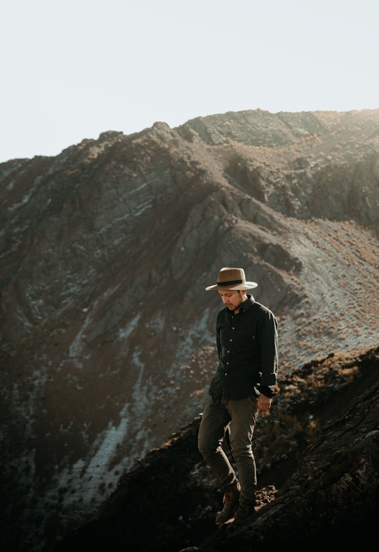 Man Wearing Hat Walking Along Mountain Top