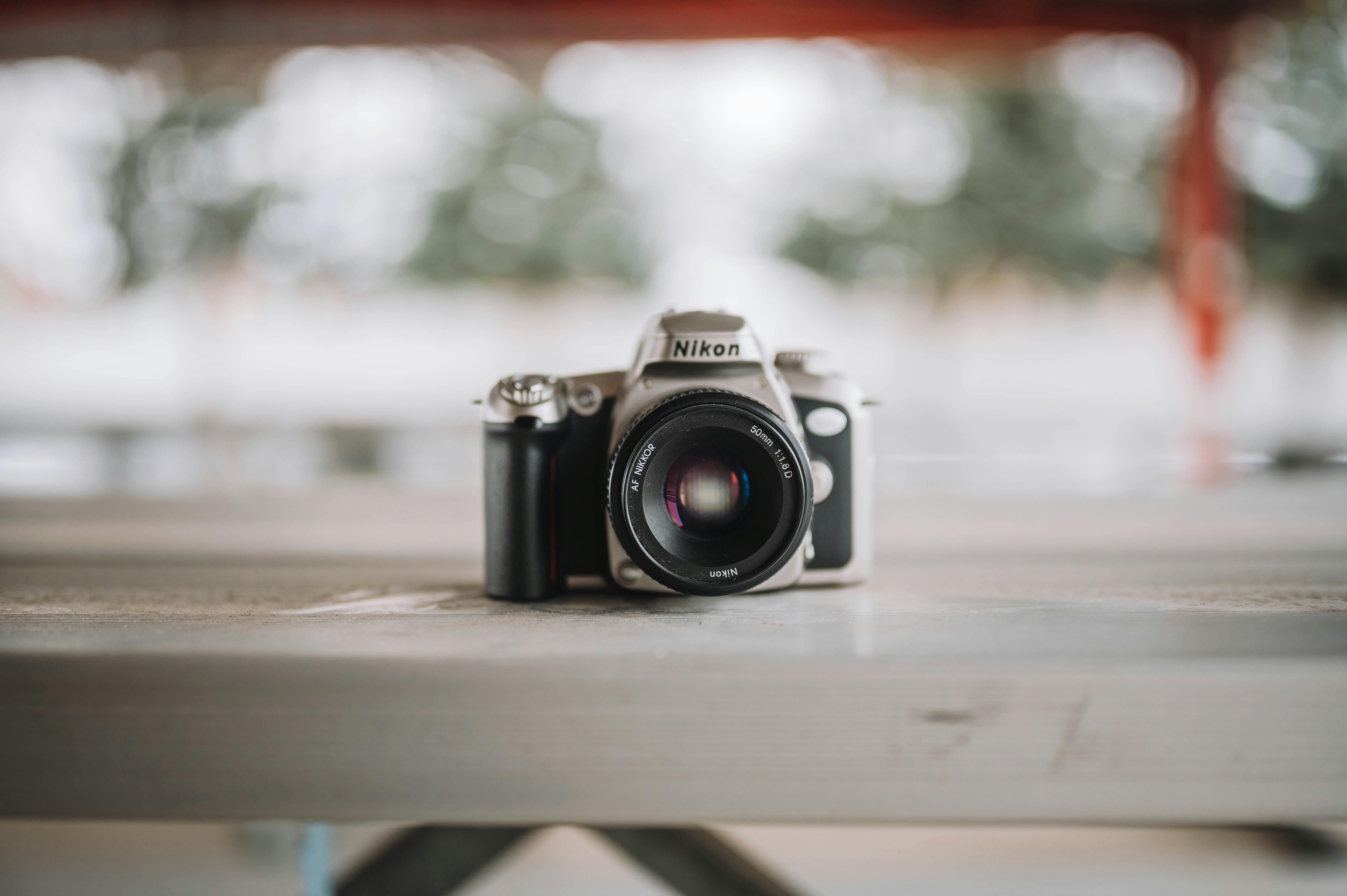 Close-up of a classic Nikon camera on a wooden surface, highlighting its vintage design and lens focus.