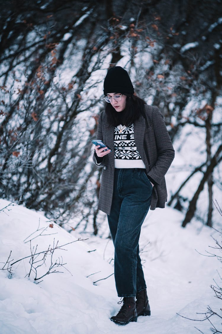 Woman Walking Through Winter Park Using Phone