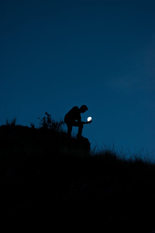 Silhouette of Man Holding Moon 