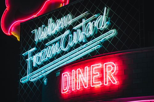 Free Colorful neon signs illuminate a retro diner at night, creating a nostalgic ambiance. Stock Photo