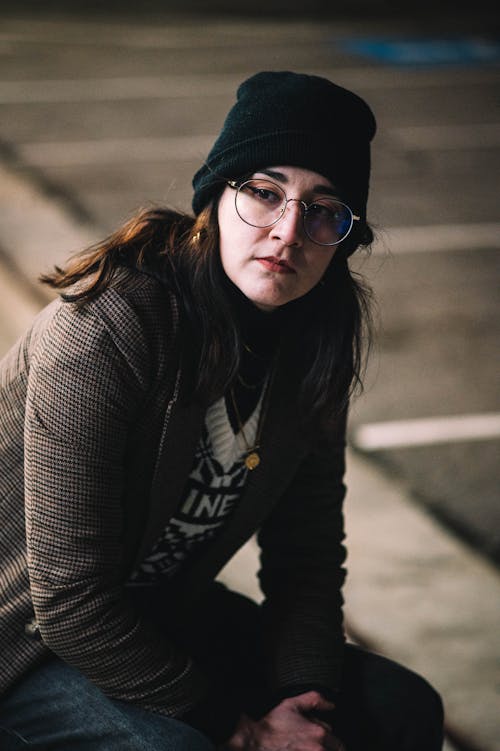 Portrait of a Brunette Wearing a Knit Hat and Eyeglasses Sitting Outdoors