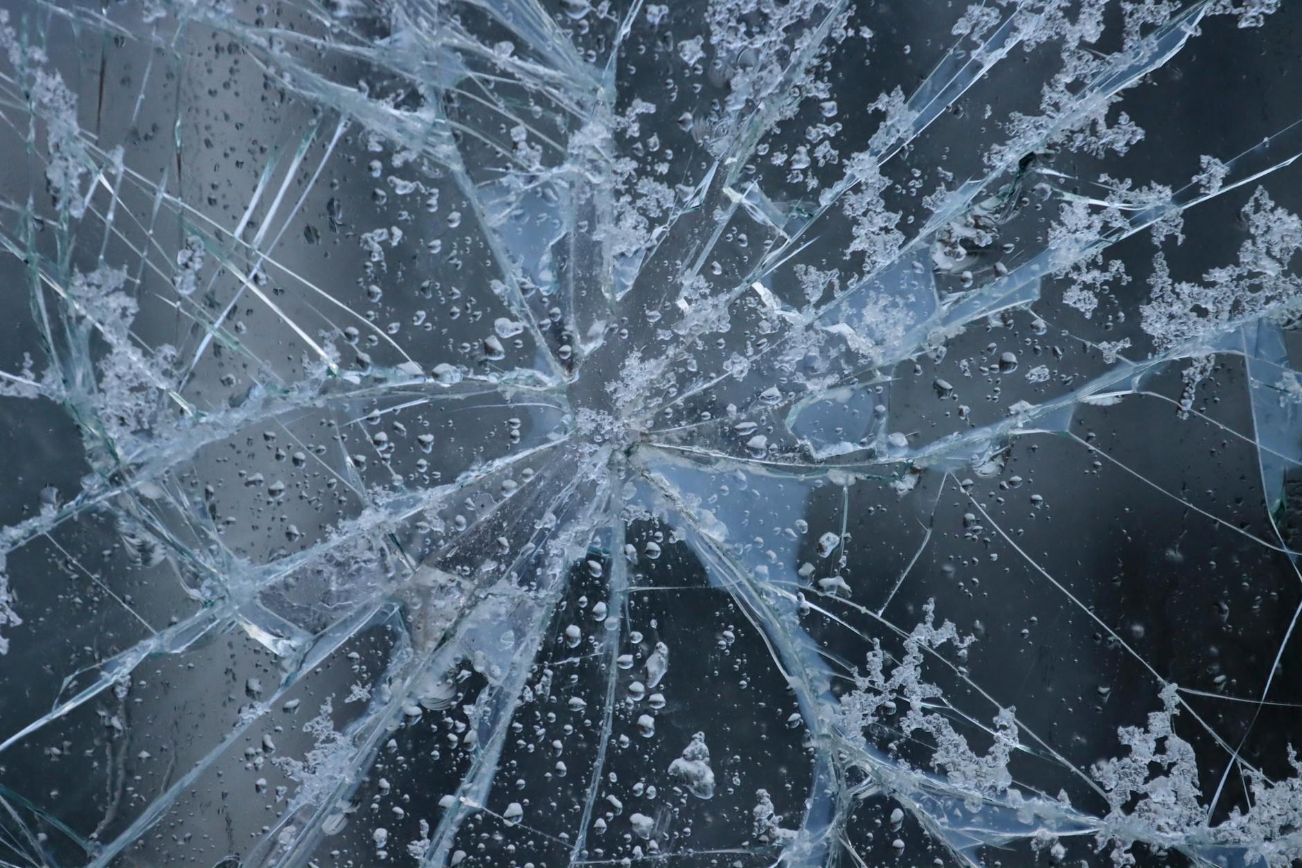 A close-up view of shattered glass with frost and water droplets, evoking winter in Sweden.
