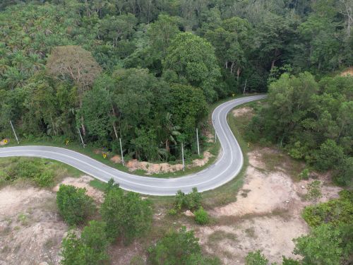 Free Aerial view of a winding road cutting through dense forest near Lumut, Malaysia. Stock Photo