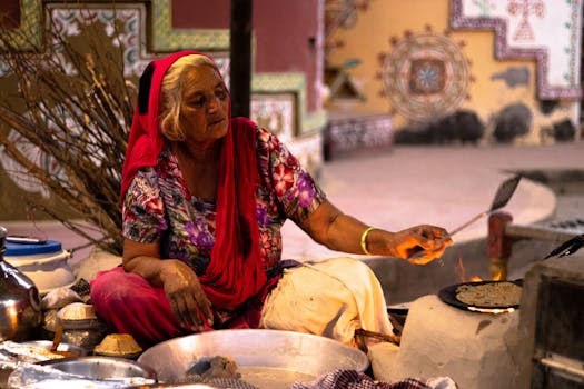 Elderly woman cooking with traditional Indian tandoor outdoors.
