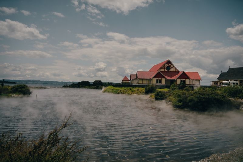 Casa tradicional maorí frente al lago de Rotorua con vapor geotérmico saliendo del agua