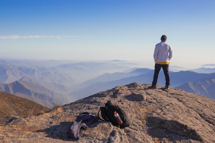 Man In Blue Jacket Standing On Mountain 