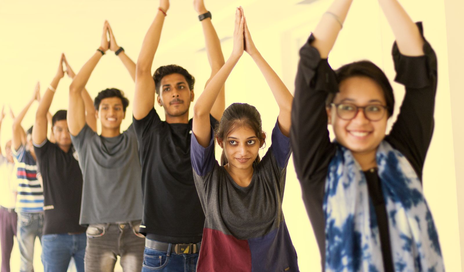 Group of young students practicing yoga poses together in a bright classroom