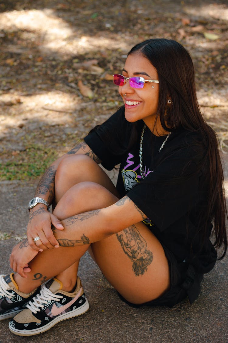 Smiling Girl With Tattoos Sitting On Ground