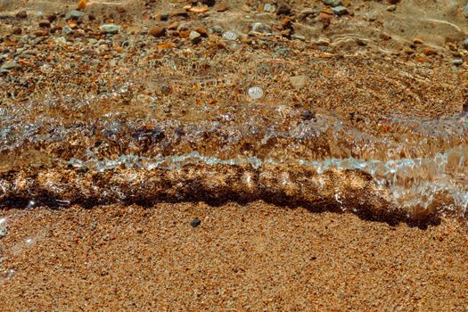 Close-up of gentle waves on a sandy beach capturing the serene coastal shoreline and pebbles.