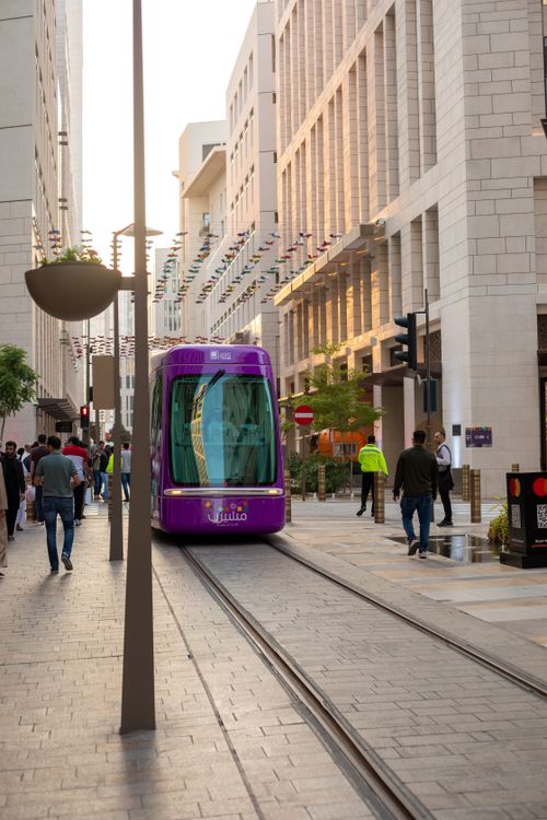 Free Vibrant tram navigating through the modern architecture of Doha, showcasing public transportation in Qatar. Stock Photo
