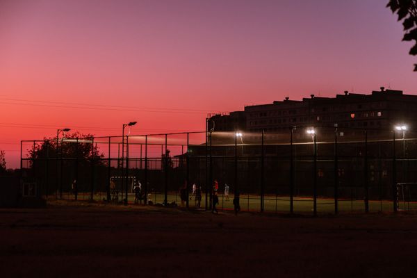 Silhouetted players on a floodlit city pitch under a magenta sunset — photo by Collab Media on Pexels