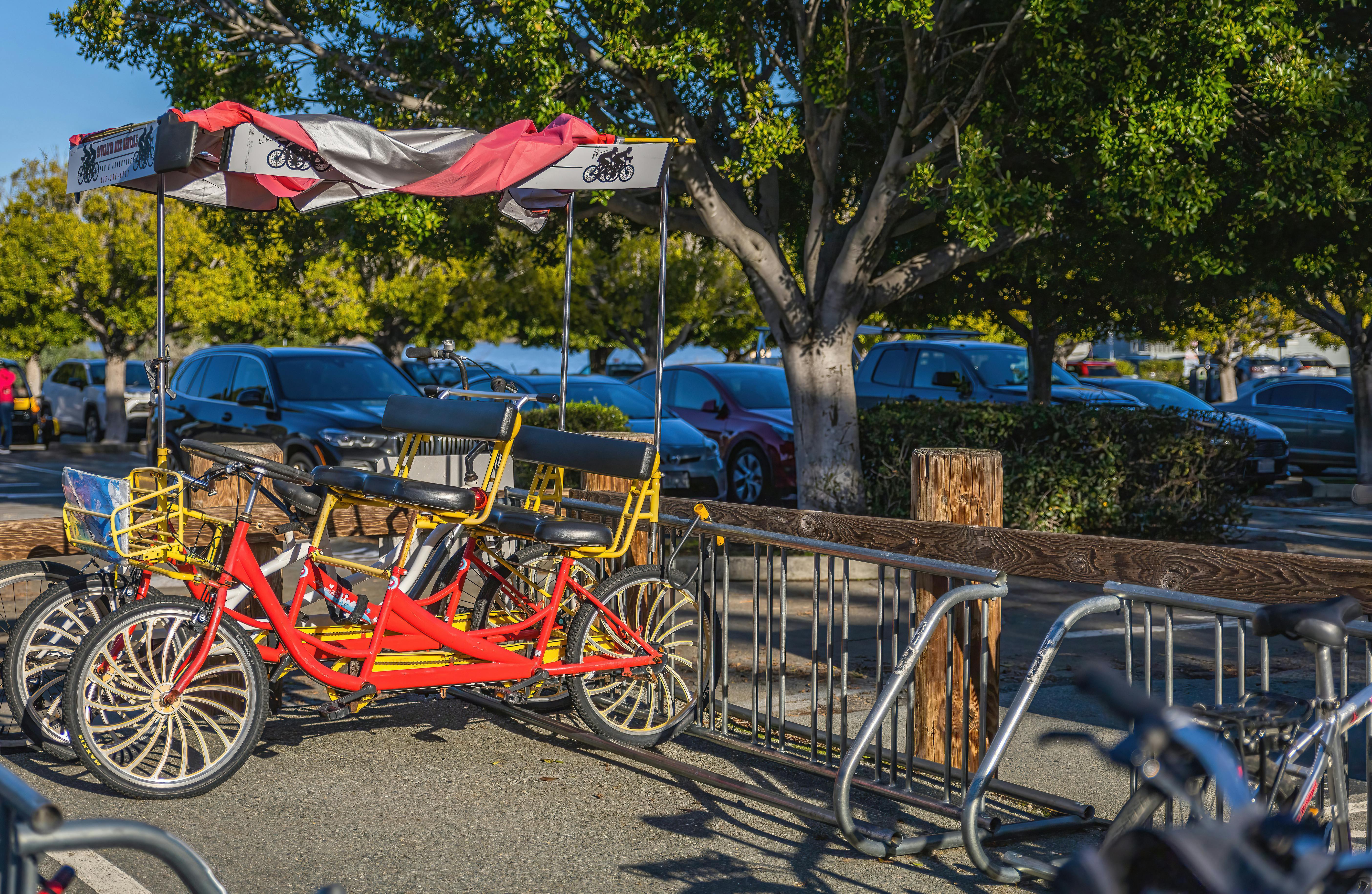 A colorful quadricycle parked in a lively park setting under a sunny sky.