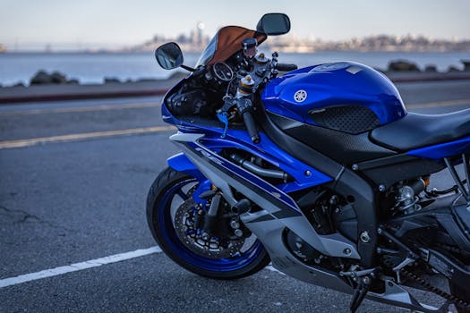 Vibrant blue Yamaha sports motorcycle parked near waterfront with cityscape in background.