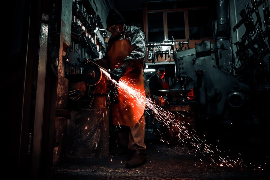 Metalworker grinding a component with sparks