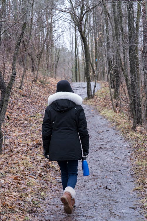 A Person in Jacket while Walking on the Pathway
