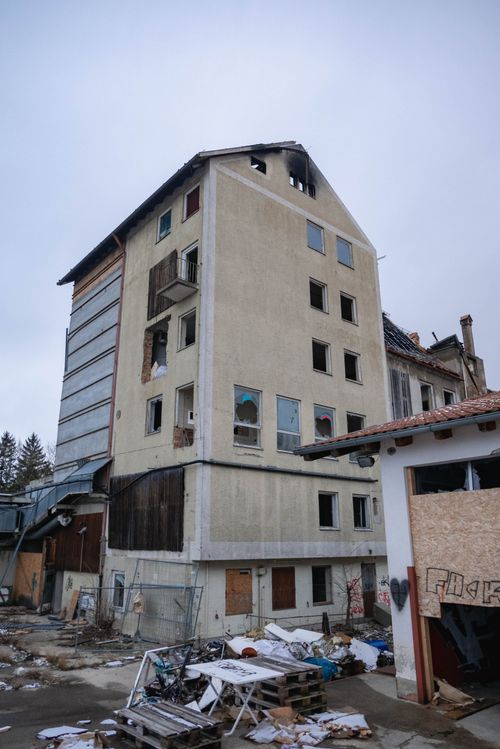 Free A tall abandoned and damaged residential building in an urban setting, showing signs of neglect. Stock Photo