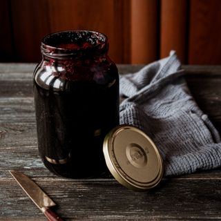 Jar of homemade blackberry preserve with a knife and cloth on a rustic table — photo by Boryslav Shoot on Pexels