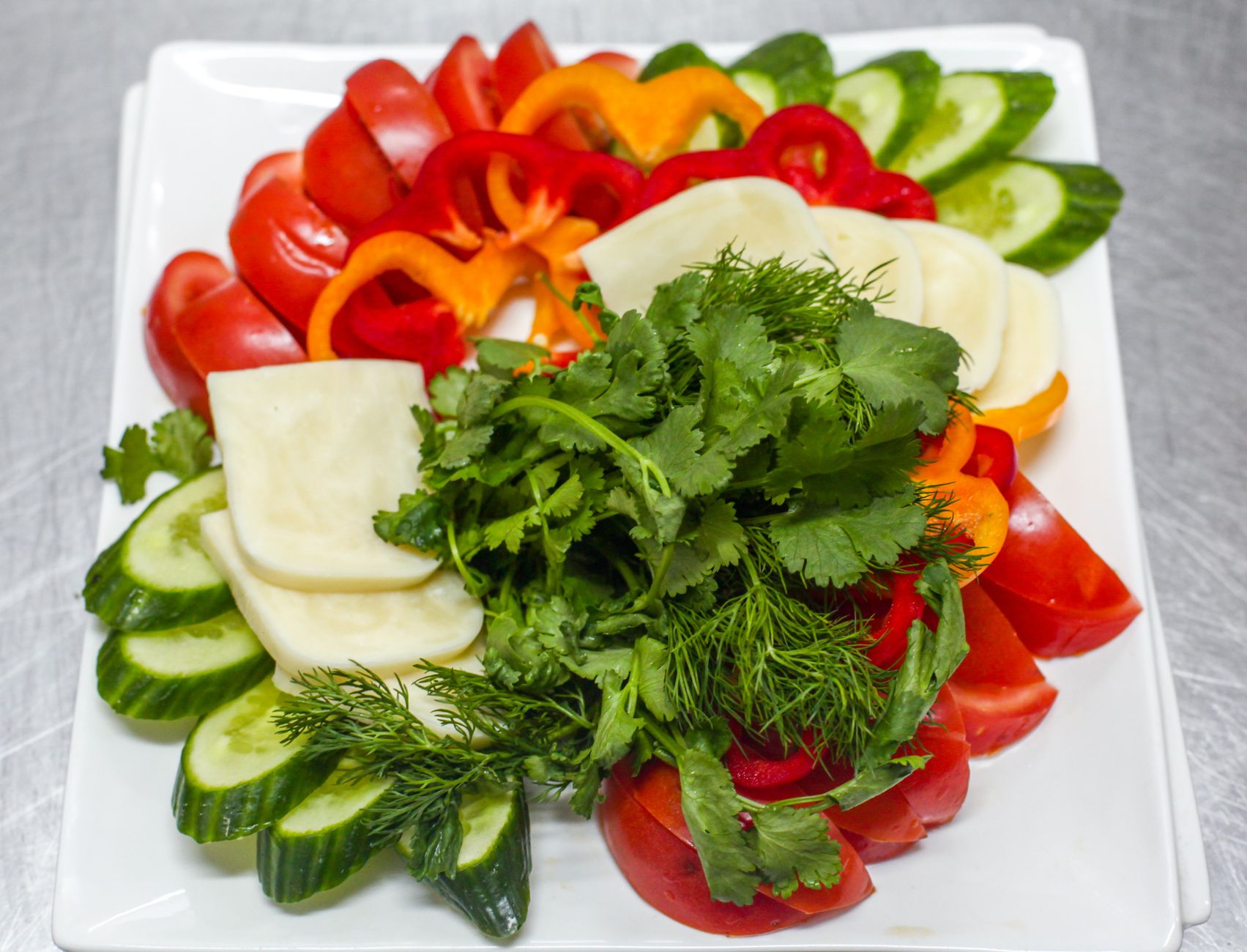 Colorful assortment of fresh vegetables and herbs on a platter for a healthy meal.