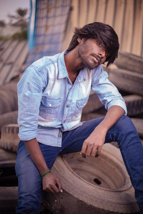 Free Casual portrait of a young man in blue denim, sitting outdoors in Chennai, India. Stylish and relaxed. Stock Photo