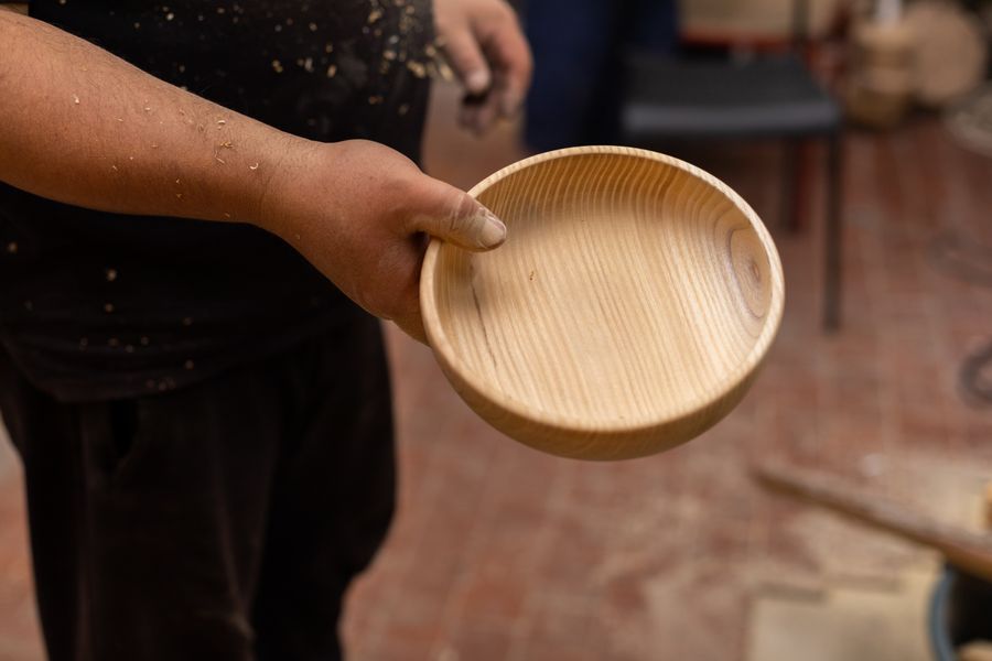 A handmade wooden bowl held in a workshop
