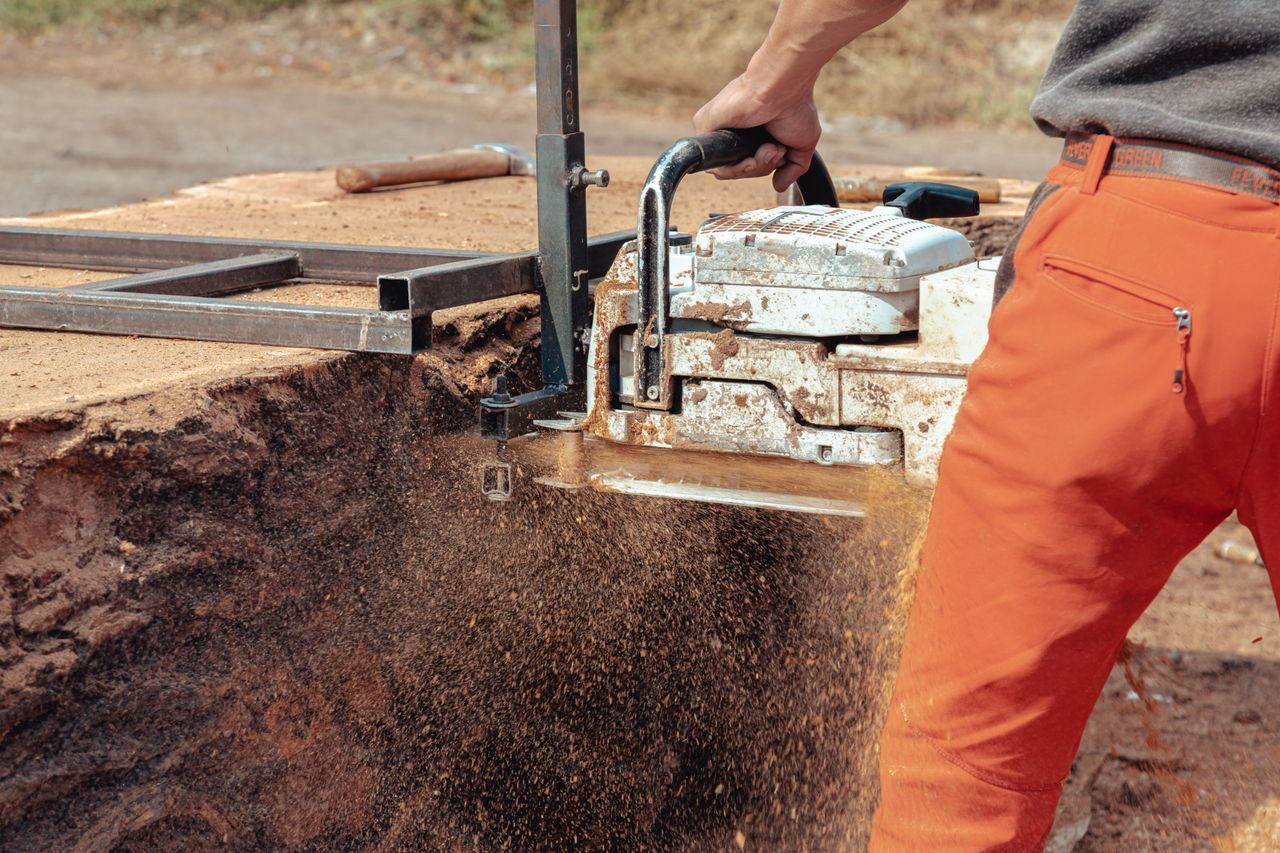 close up of a worker operating a chainsaw to cut wood at a constructio
