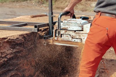 Worker in safety equipment operating a chainsaw at a job site
