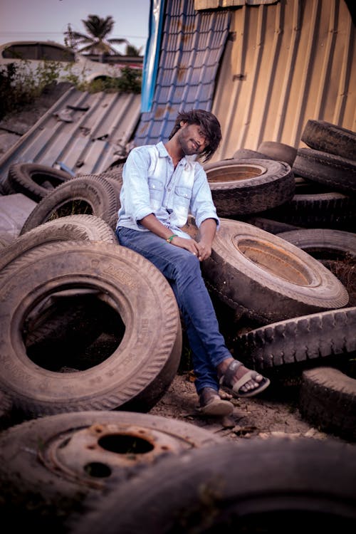 Man Sitting on Old Tires