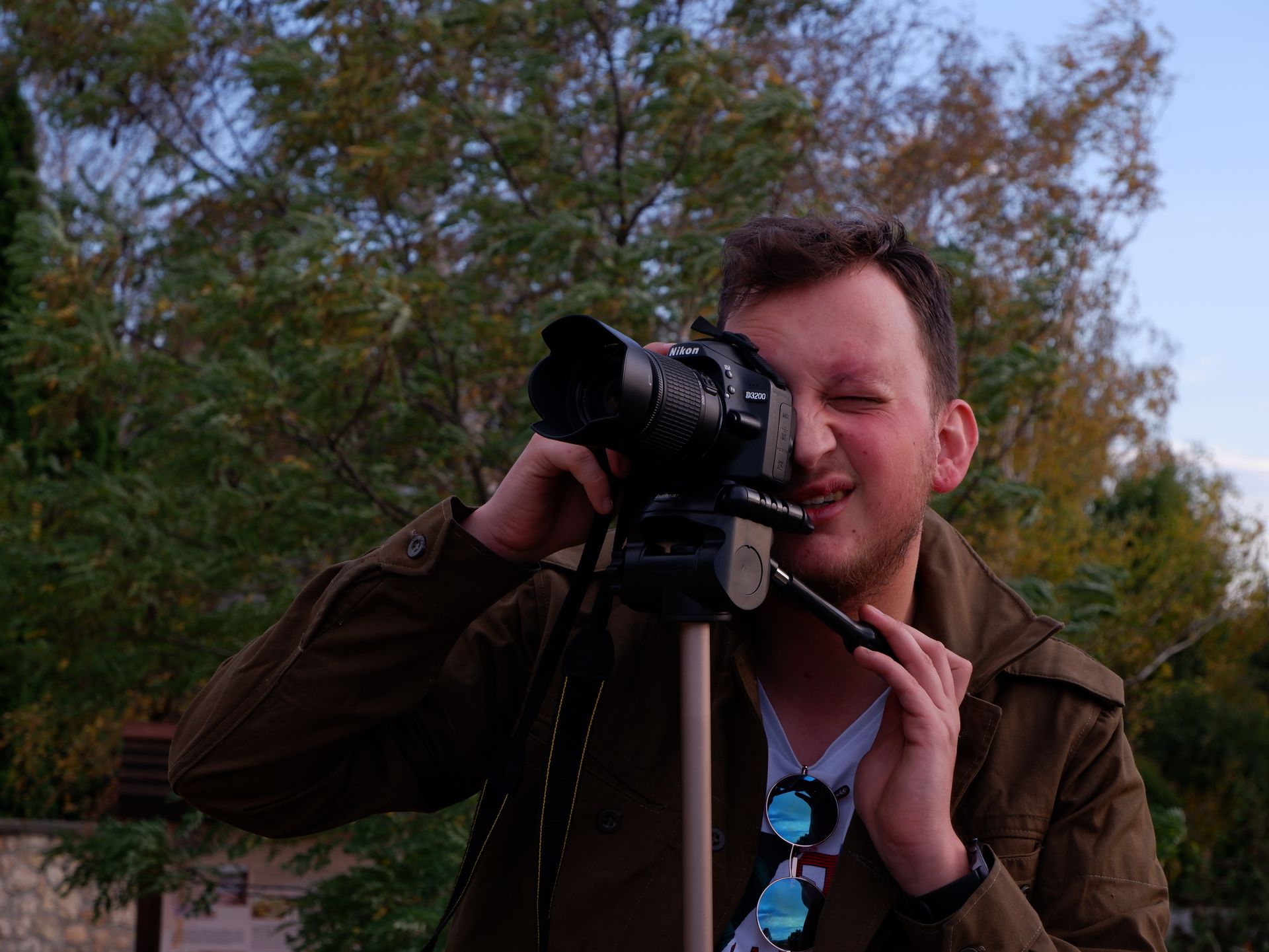 A professional photographer capturing nature with a DSLR camera on tripod outdoors.