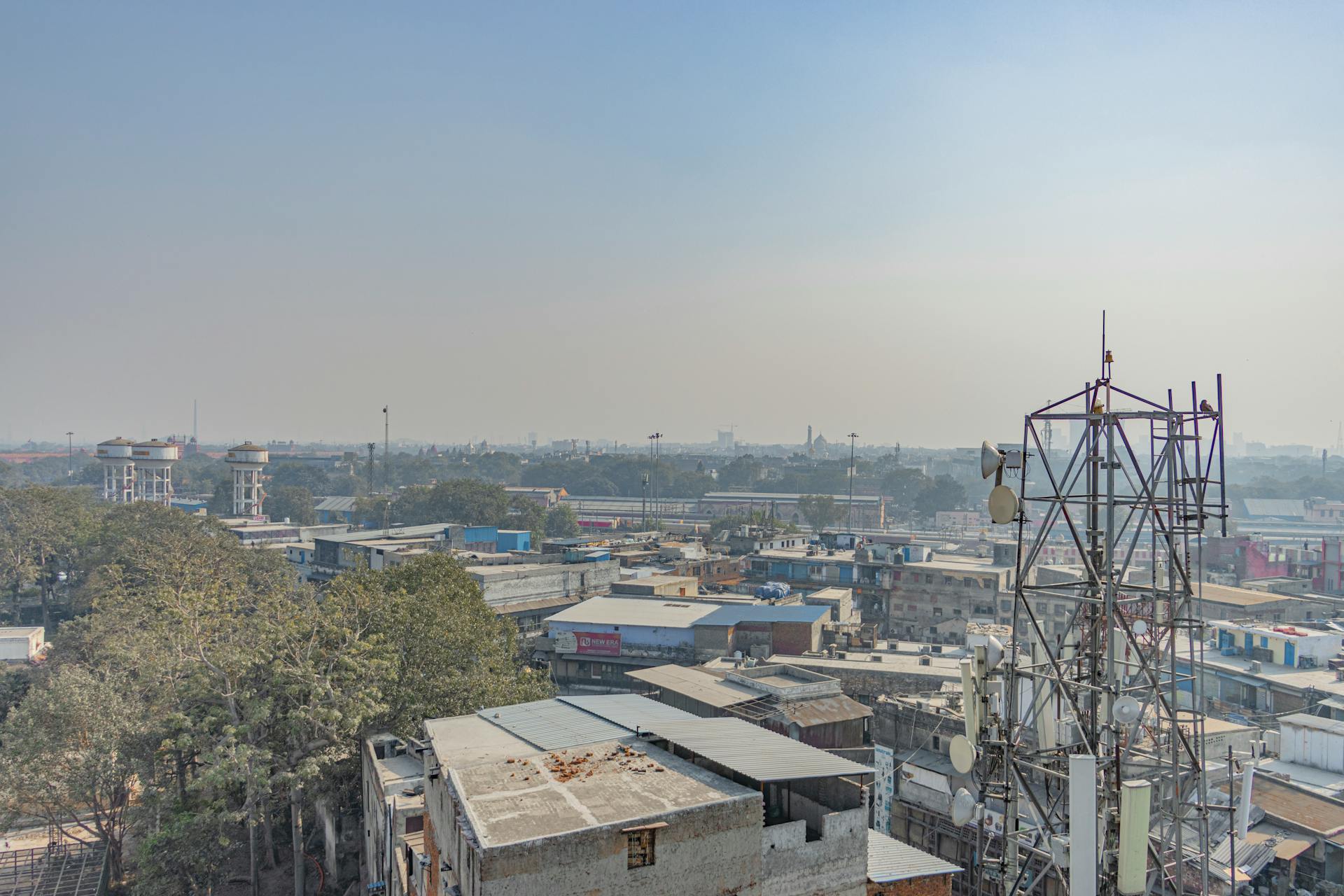 Aerial view of urban buildings and trees with a telecom tower in New Delhi, India.