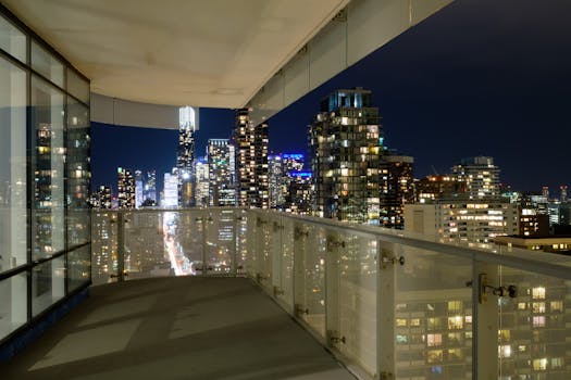 Stunning nighttime view of a modern city skyline from a high-rise balcony.