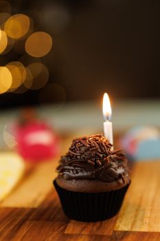 Tasty chocolate cupcake with a lit candle, perfect for birthdays or celebrations. Captured in a warm, inviting setting.