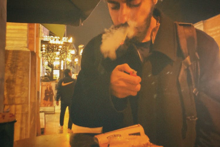 Film Photograph Of A Man Standing Outside At Night And Smoking 